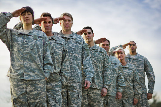 Portrait of a line of US Army soldiers saluting.