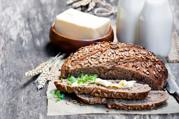 Sliced  homemade rye bread on baking paper and bottles of milk o