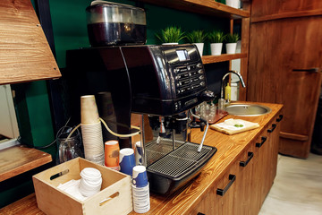 stylish coffee machine and paper cups on wooden desk. take to go