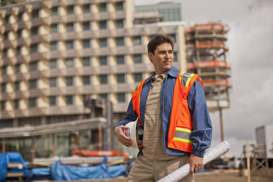 Young architect standing with blueprint at construction site