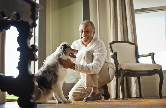 Portrait of a smiling mature man petting his dog.