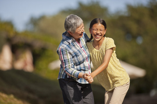 Smiling senior woman playfully dancing with her granddaughter.