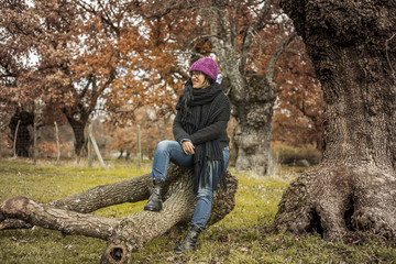Naklejka na ściany i meble Portrait woman looking away sit on a tree trunk. Autumn field la
