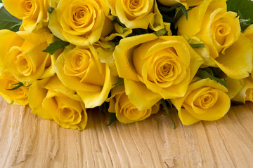 Yellow roses over wooden table. 