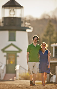 Husband and wife walking in front of lighthouse.