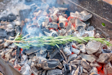Coal fueled BBQ grill. For flavor is a branch of rosemary.