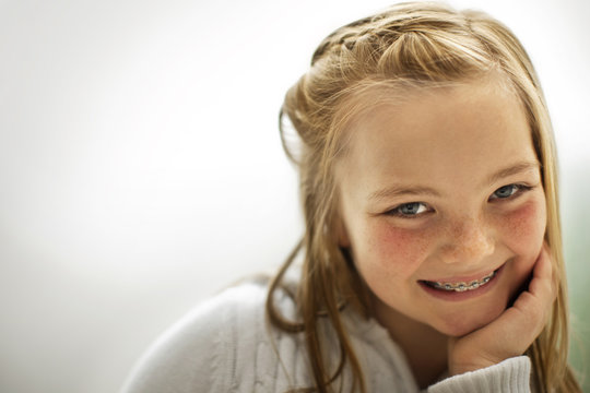Portrait of a smiling young girl with her hand on her chin.