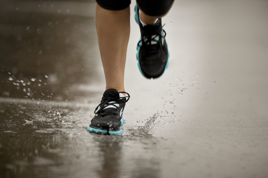 Young woman jogging on a residential street in the rain.