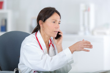 serious female dentist looking at report while using cellphone