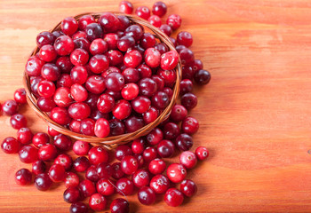 Fresh cranberries in a small basket on a wooden background
