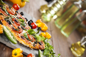 Tasty pizza, tomatoes and others ingredients on a wooden backgro