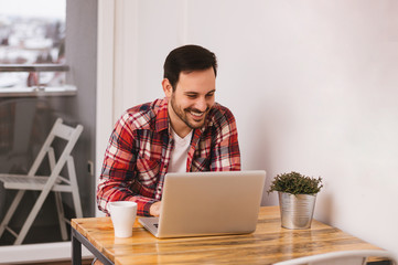 Handsome man working on a computer and drinking coffee.