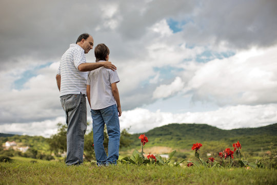 Mature man walking through field with his young son.