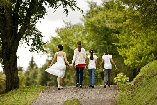 Mature woman walking and holding hands with her daughters.