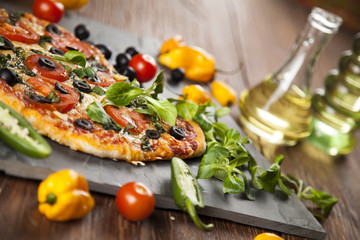 Tasty pizza, tomatoes and others ingredients on a wooden backgro