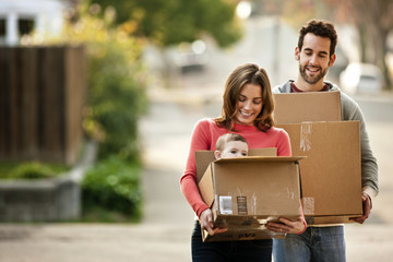 Mid-adult couple carrying their baby in a moving box.