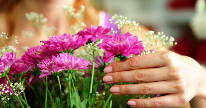 Close-up of female florist arraigning flower bouquet in flower shop