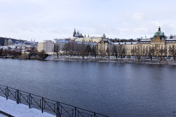 Obraz premium Snowy freeze Prague Lesser Town with gothic Castle above River Vltava, Czech republic