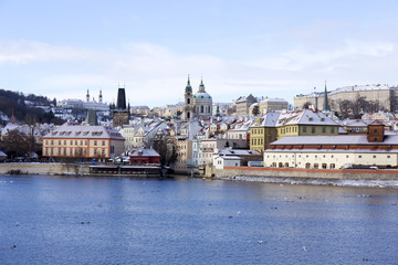 Fototapeta premium Snowy freeze Prague Lesser Town with St. Nicholas' above River Vltava, Czech republic 