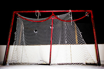 Close-up of tattered and frayed mesh on a hockey net on an outdoor ice skating rink at night