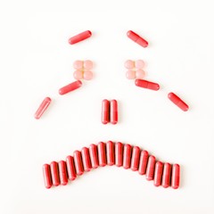 Sad and crying smile made from many pills capsules. wellness concept