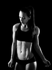 Obraz na płótnie Canvas Young sporty woman posing on black background. Black and white photo