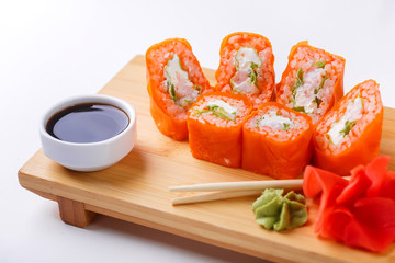 nori rolls in orange in the sauce on a wooden stand