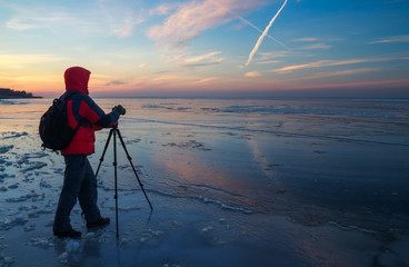 Photographer take pictures on the frozen river during sunset