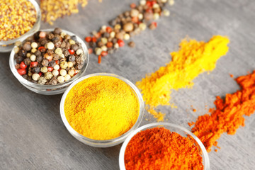 Various spices in glass bowls on grey table