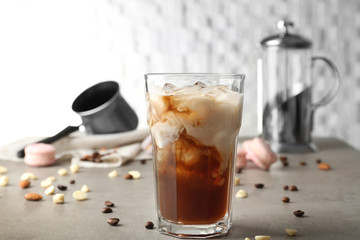 Glass of cold coffee with milk on table