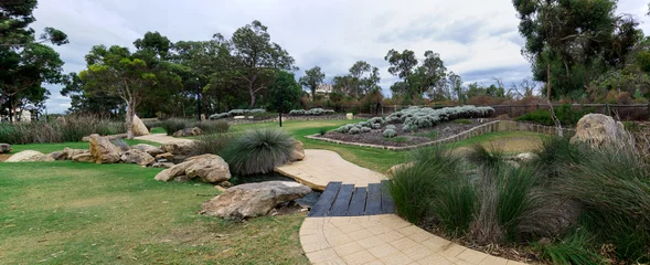 Fototapeten Panoramic view of walkpath, gardens and water stream in Joondalup, Western Australia © anastasstyles