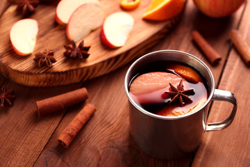 Cup of delicious Christmas mulled wine on wooden background, closeup