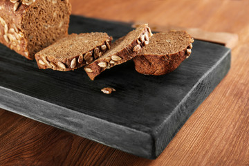 Sliced rye bread with seeds on wooden cutting board closeup