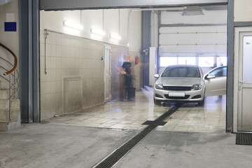 Servicemen (he is blurred) washes an automobile in a car wash