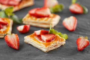 Sweet tasty pastries with fresh strawberries on textured background