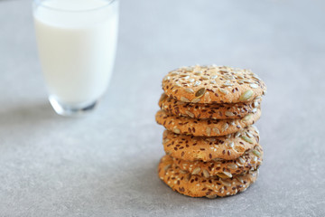 Delicious cereal cookies with glass of milk on color background