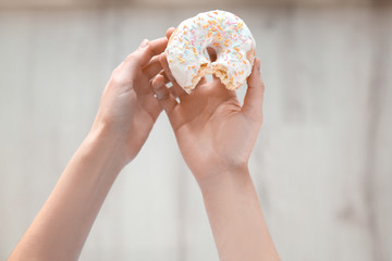Close up view of woman with tasty donut on blurred background. Dieting concept