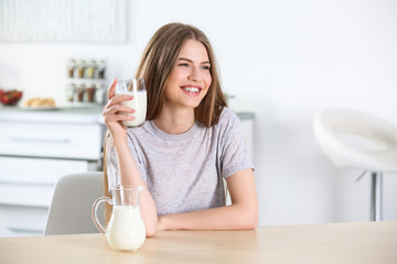 Beautiful young woman drinking milk at home