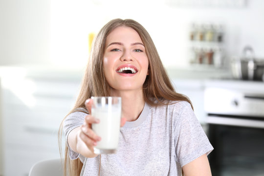 Beautiful young woman with glass of milk at home