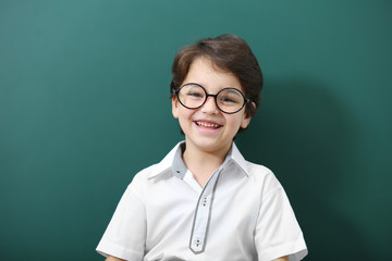 Cute little boy in glasses on green background
