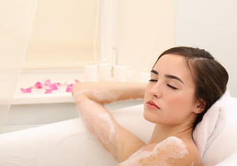 Obraz na płótnie Canvas Young beautiful woman taking relaxing bath with foam