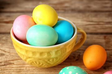 Obraz na płótnie Canvas Colourful Easter eggs in a mug on wooden background
