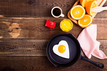 Heart shape fried egg, fresh orange juice and coffee. Top view
