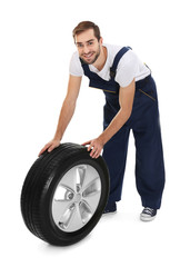 Young mechanic in uniform with wheel on white background
