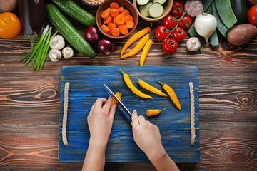 Female hands cutting pepper at table, top view