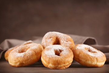 Tasty donuts with powdered sugar on table