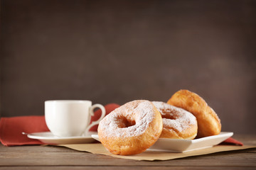 Tasty donuts with cup of coffee on table