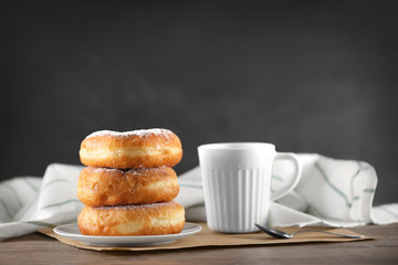 Tasty donuts with cup of coffee on gray background