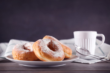 Tasty donuts with cup of coffee on table