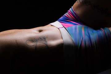 Closeup of stomach and hips of an athletic young asian woman with tattoos